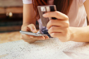 Woman is making online shopping with mobile phone. She use credit card and the smartphone.